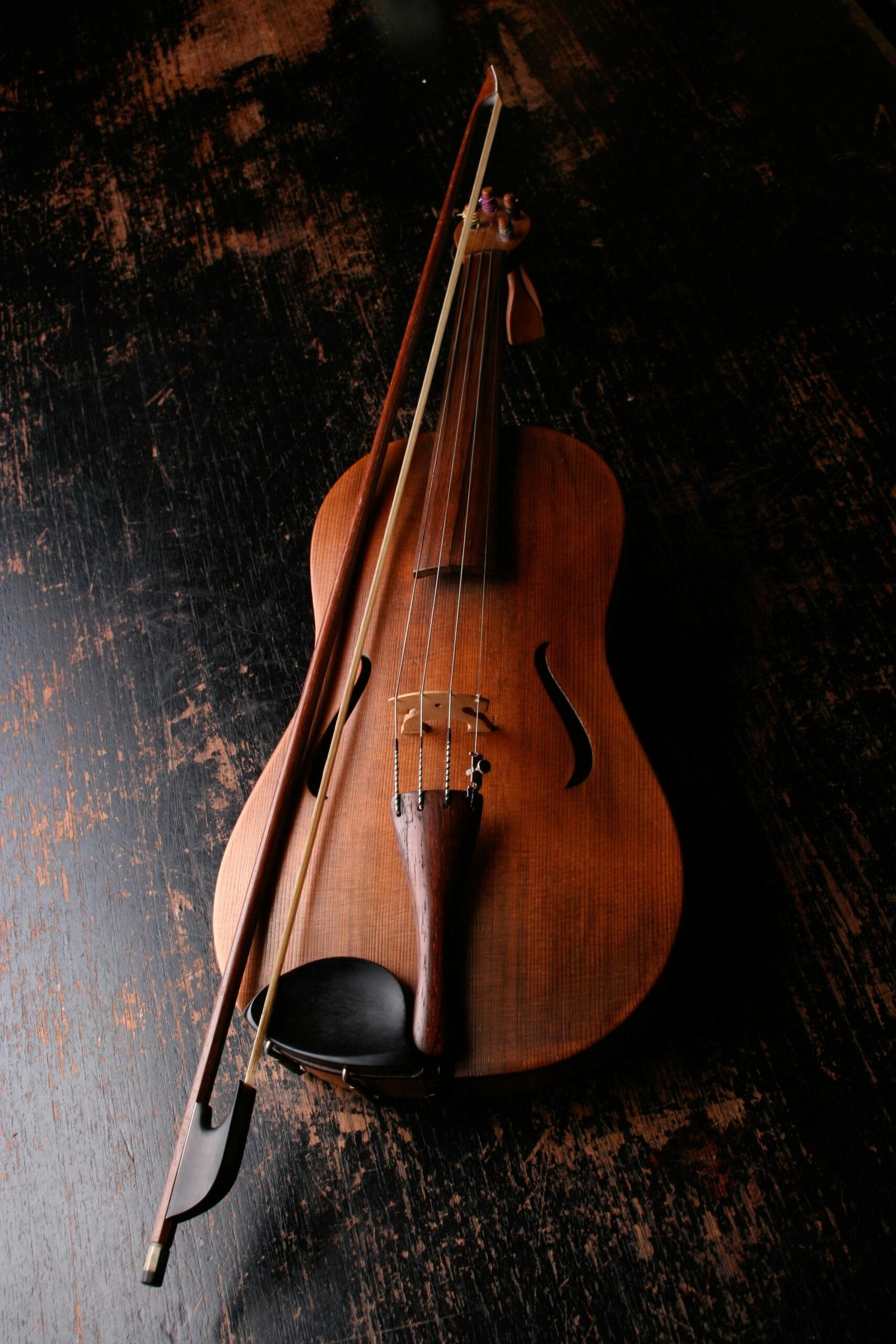 A beautifully crafted violin rests on a dark wooden surface, evoking a classic and artistic mood.
